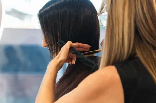 Stylist combing and trimming dark hair
